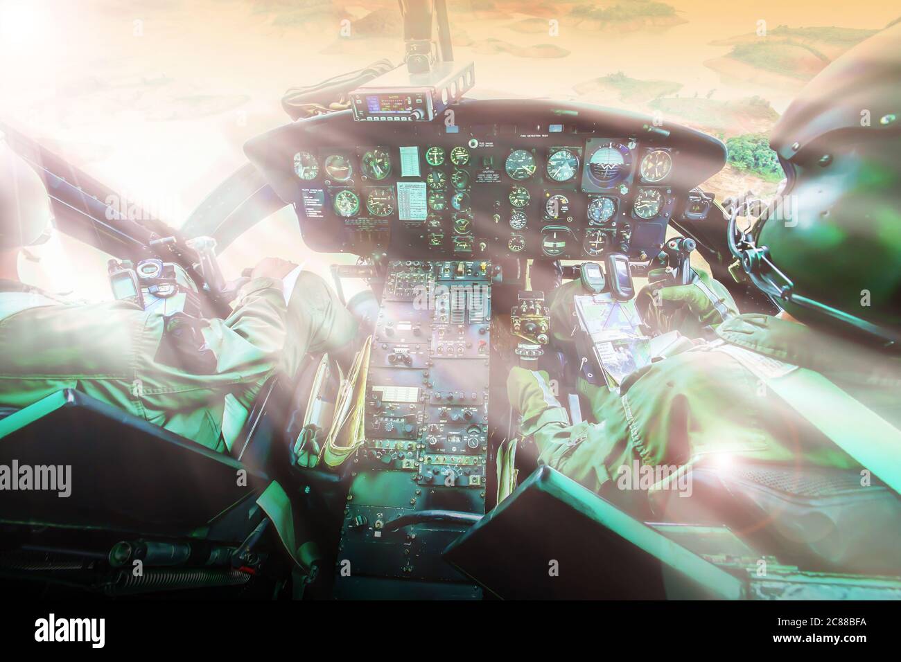 Cabina di pilotaggio militare con due piloti che volano contro il tramonto su un lago e una catena montuosa. Mettere a fuoco il pannello di controllo. Foto Stock