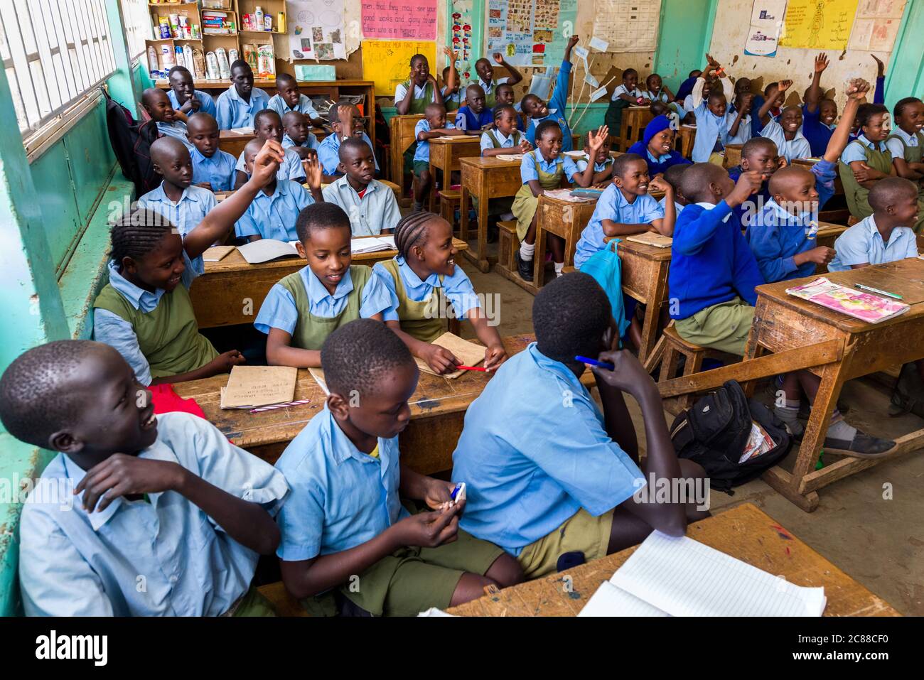 I bambini della scuola secondaria in uniforme si sedevano a banchi di legno ascoltando il loro insegnante durante la lezione, Nairobi, Kenya Foto Stock
