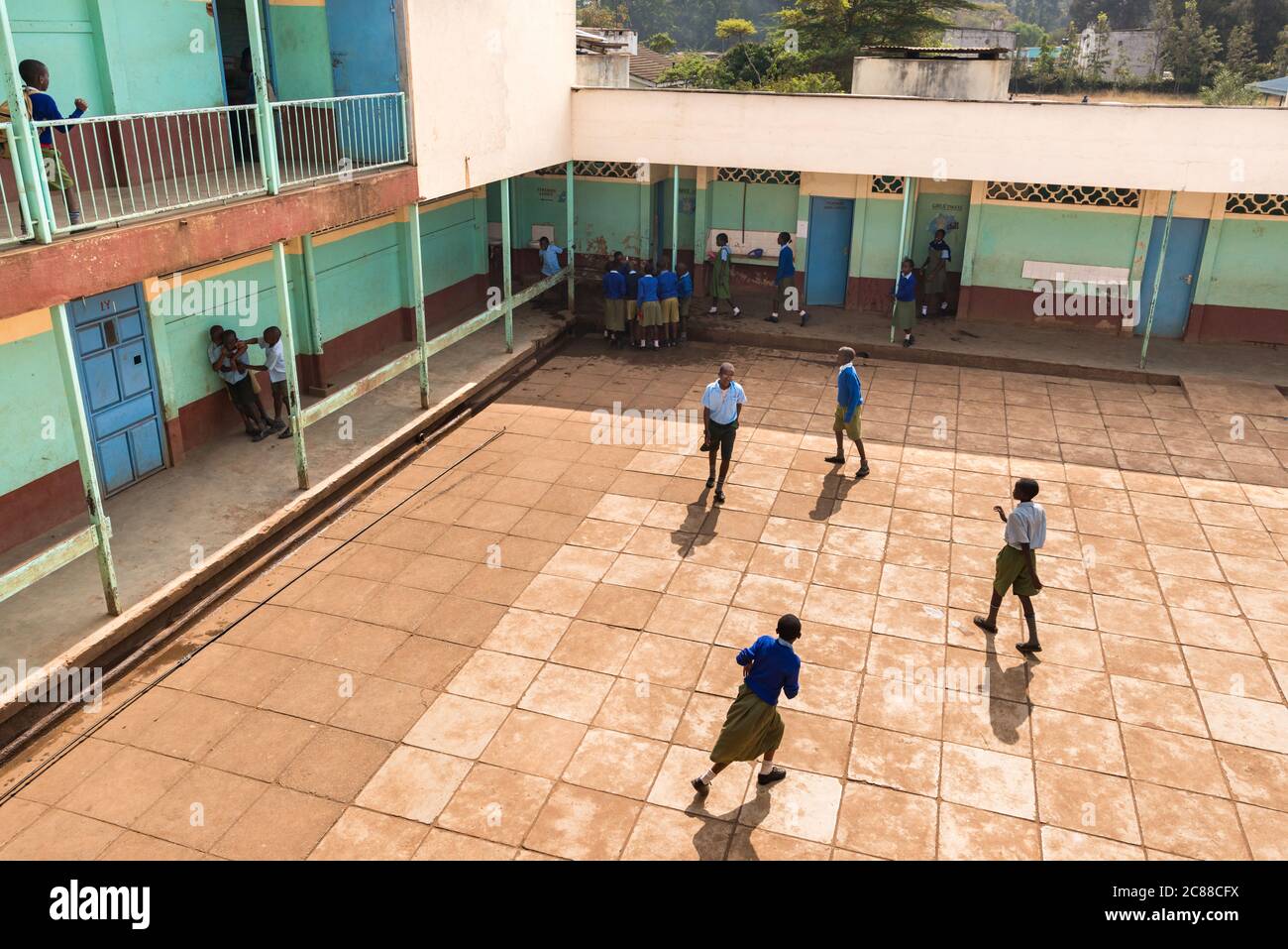 Vista esterna della scuola secondaria con cortile e bambini in uniforme, Nairobi, Kenya Foto Stock