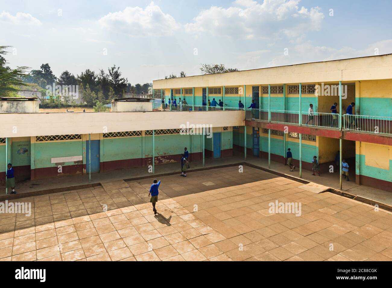 Vista esterna della scuola secondaria con cortile e bambini in uniforme a piedi per classe, Nairobi, Kenya Foto Stock