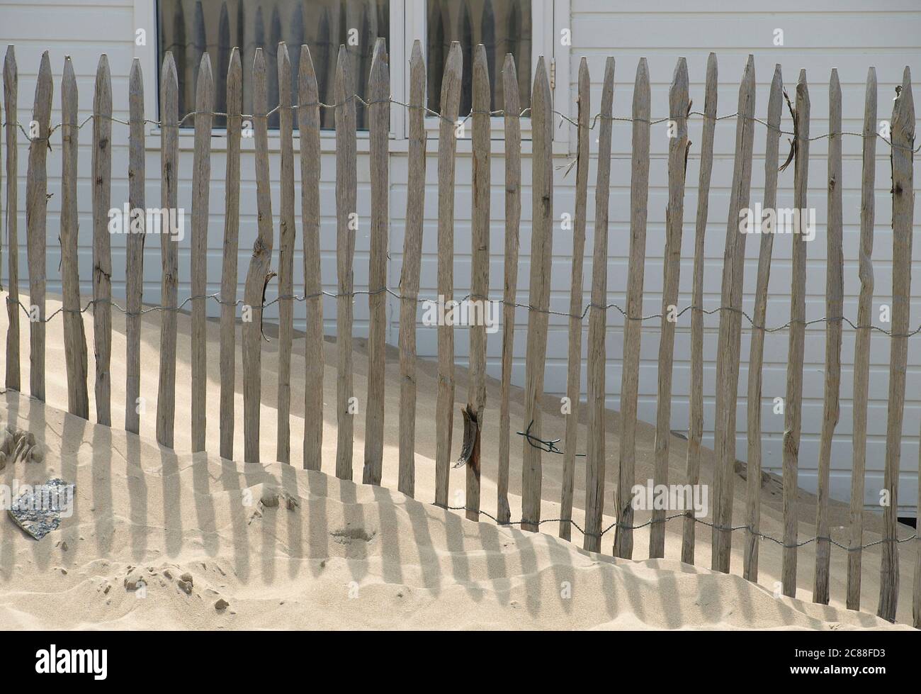 Recinzione in legno sulla spiaggia di fronte ad una piccola casa Foto Stock