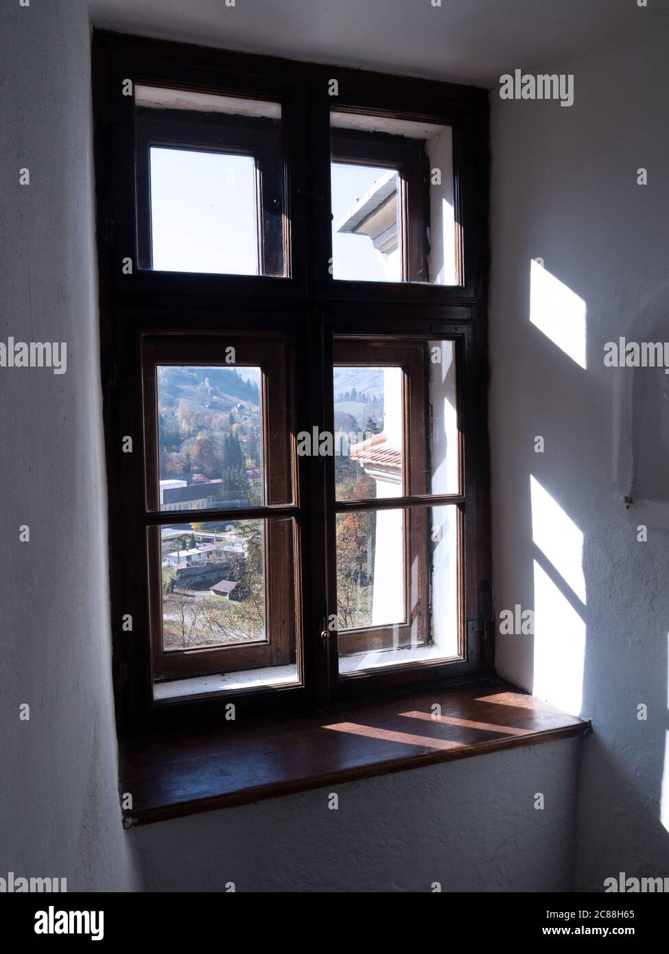 La luce del sole splende attraverso la finestra incorniciata in legno del castello di Bran, a due strati, guarda a una bella vista esterna. Foto Stock