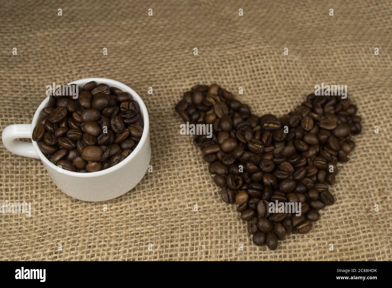 Forma a cuore fatta da chicchi di caffè e tazza di caffè con ortografia hessiana amo il caffè Foto Stock