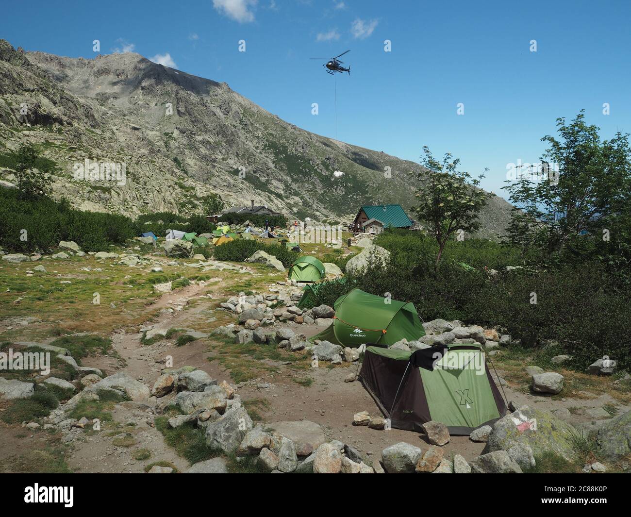 Francia, Corsica, Alpi Corsiche, 19 giugno 2017: Elicottero che rilascia le forniture per il campo di montagna Refuge de pietra piana sul famoso sentiero GR20 Foto Stock