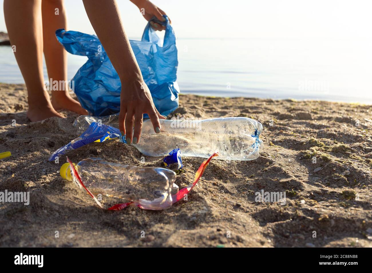 Volontario raccogliere la plastica sprecata su polluted Beach Outdoor, tagliato Foto Stock