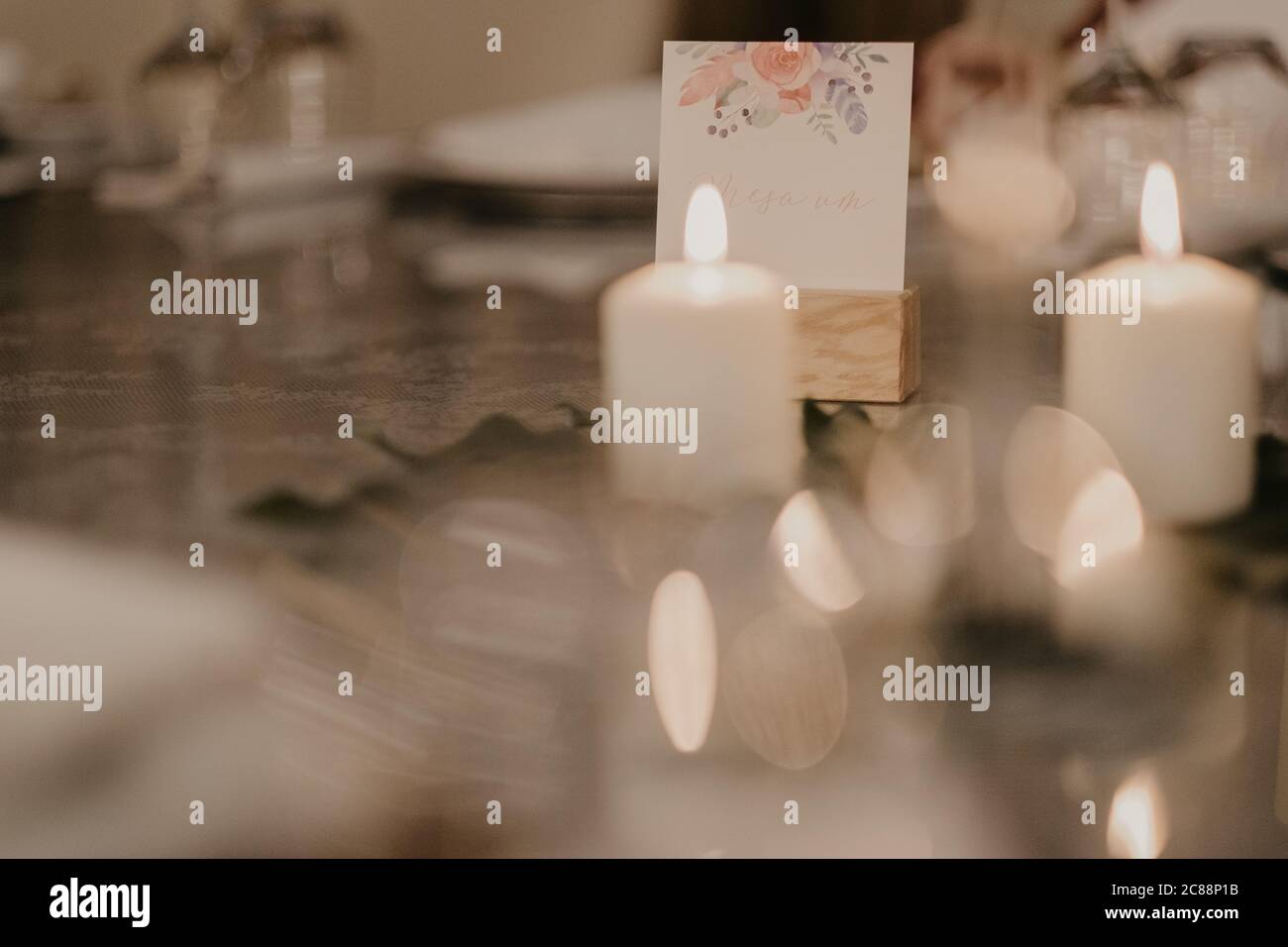 Candele bianche e una cartolina di nozze su un tavolo Foto Stock