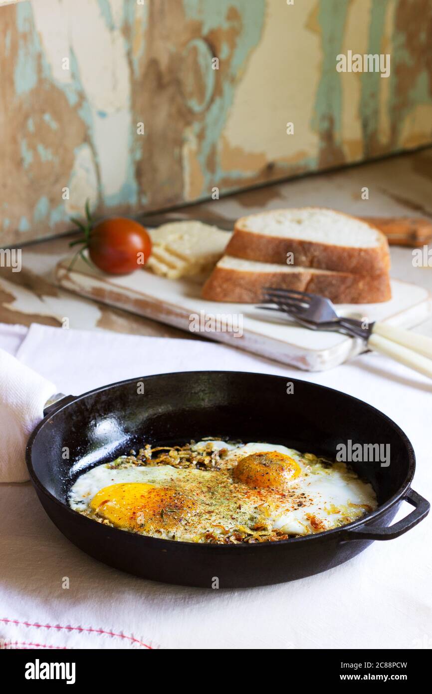Uova fritte con cipolle e spezie in una padella di ghisa. Foto Stock