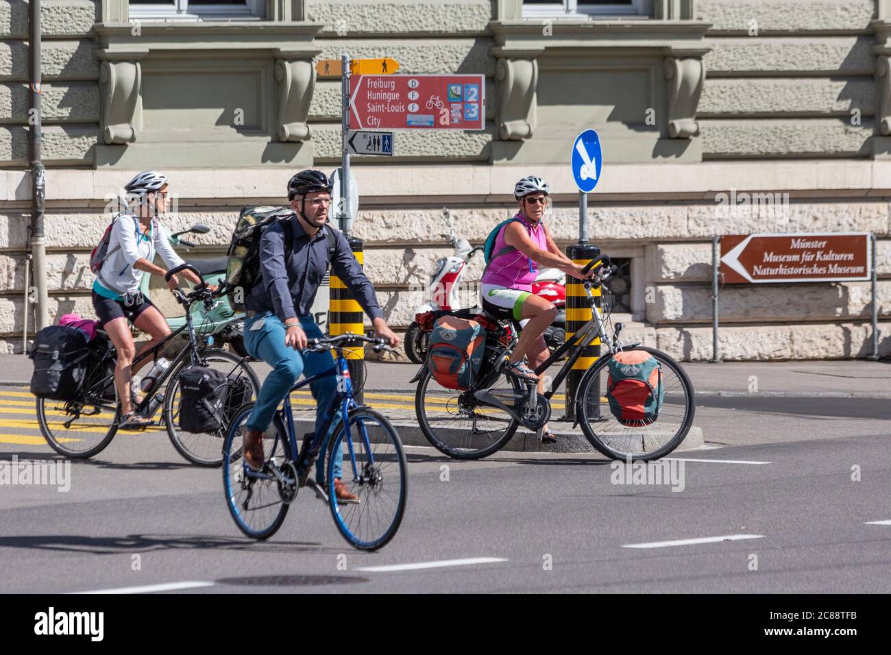 Tre ciclisti attraversano un incrocio stradale a Basilea Foto Stock