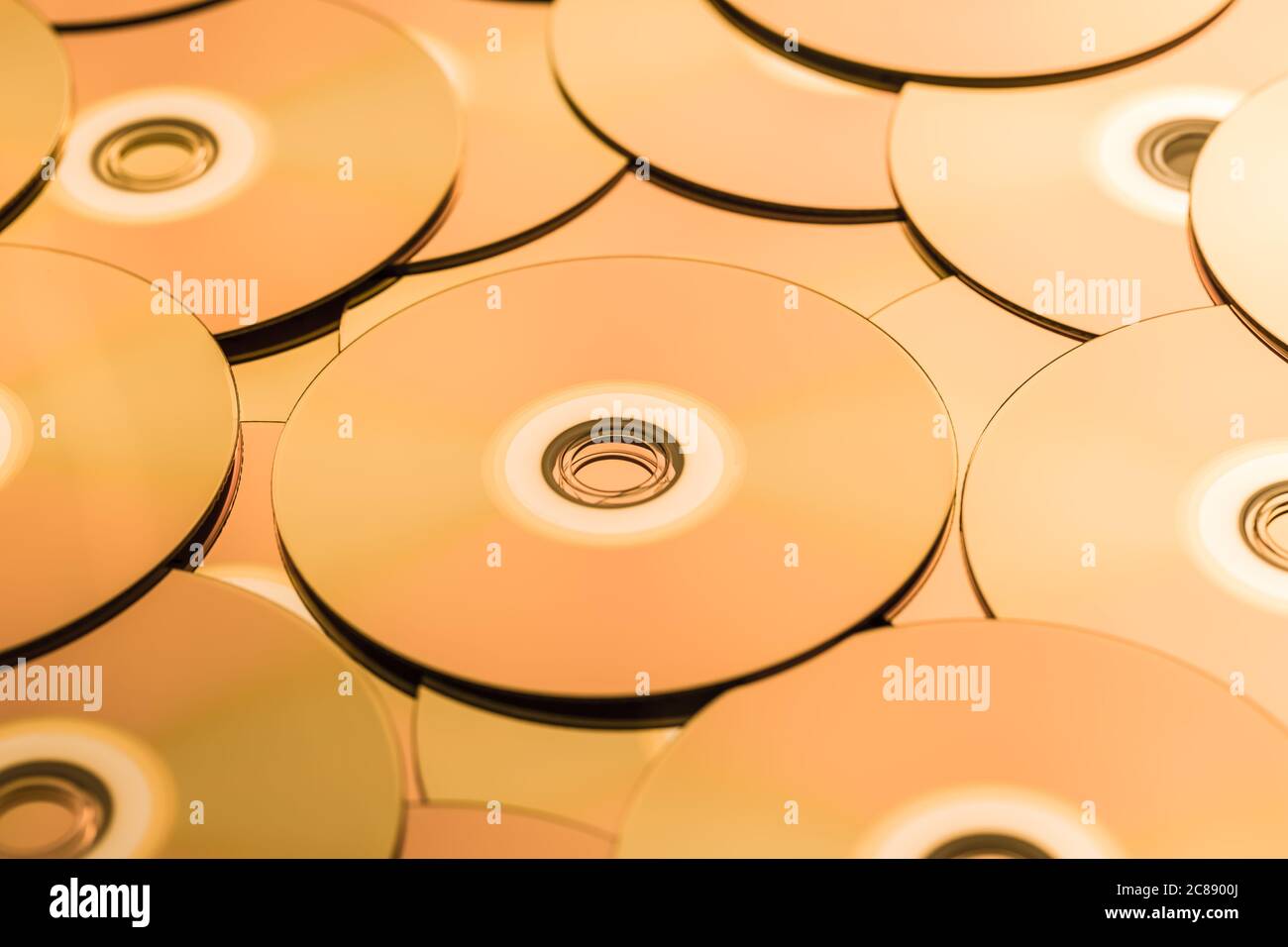 CD e DVD in tonalità dorata come sfondo. Messa a fuoco morbida. Foto Stock