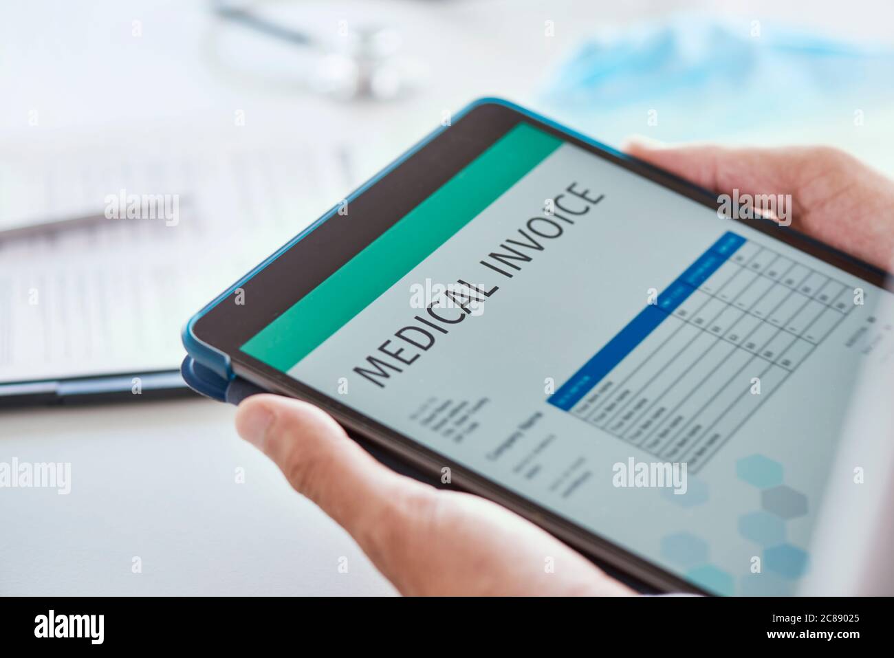 primo piano di un medico caucasico, alla sua scrivania d'ufficio, che controlla una fattura medica in un tablet digitale Foto Stock