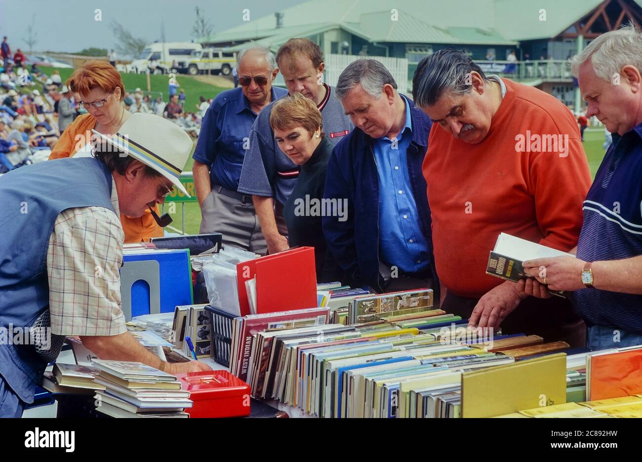 Collezionisti di libri di cricket che esplorano lo stallo di Neil Beck durante una pausa nella partita di cricket. Hastings, Sussex orientale, Inghilterra, Regno Unito Foto Stock
