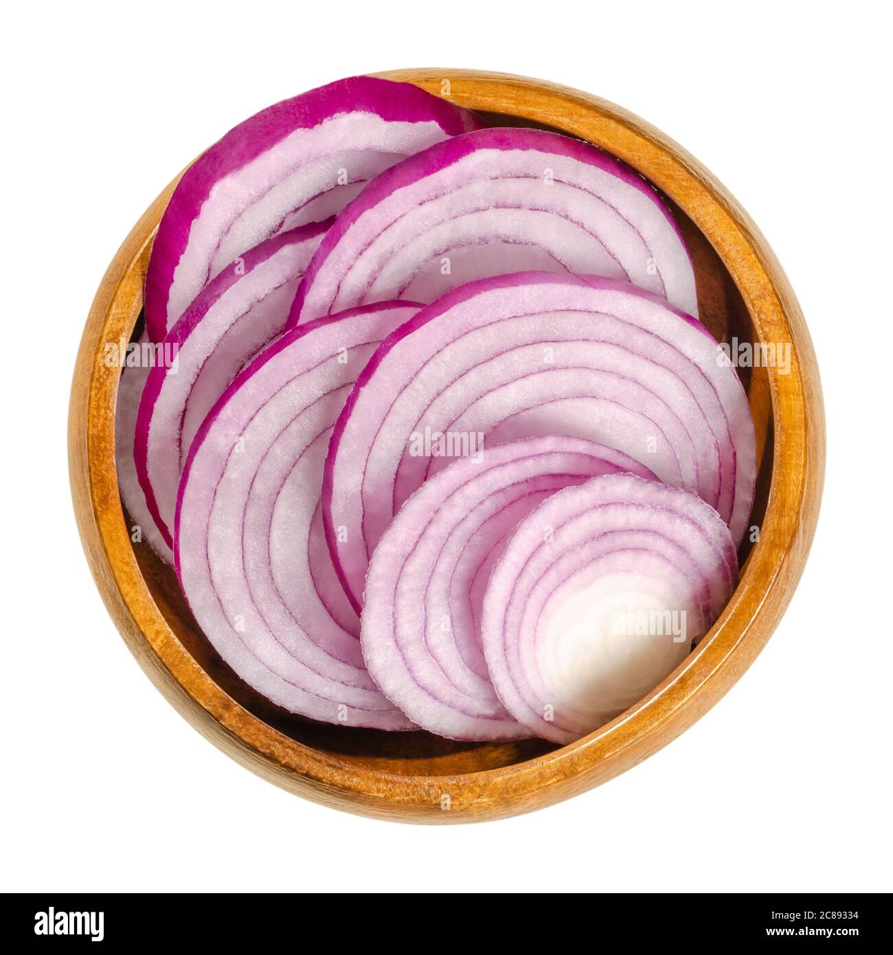 Sezioni trasversali di cipolle rosse in una ciotola di legno. Fette di cipolla Allium cepa con pelle rossa porpora e polpa bianca tinta di rosso. Foto Stock
