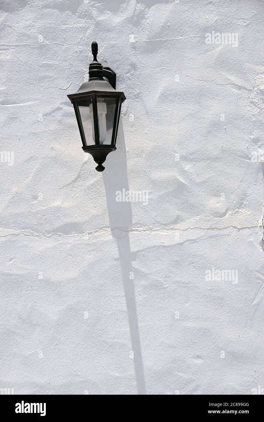 Lampada da strada e la sua ombra sulla parete intonacata bianca. Fuerteventura, isola delle Canarie. Spagna Foto Stock