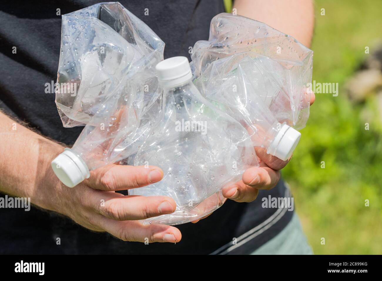 Uomo che tiene in mano bottiglie di plastica schiacciate, concept, stile di vita ecocompatibile, zero rifiuti Foto Stock