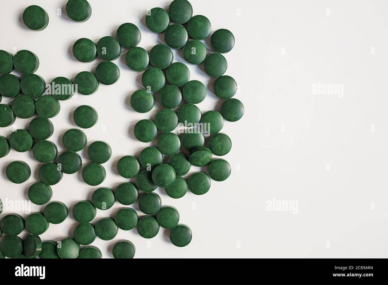 Pillole verdi su paletta di legno isolato su sfondo bianco con riflessione. Spirulina, clorella e erba del siero. Concetto di vita sano. Foto Stock