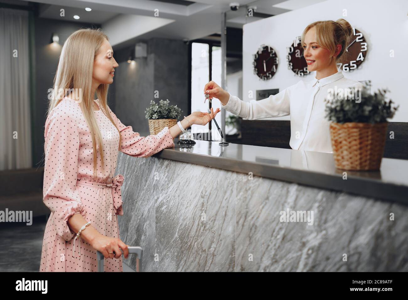 Giovane ospite dell'hotel che riceve la chiave di accesso dall'addetto alla reception Foto Stock