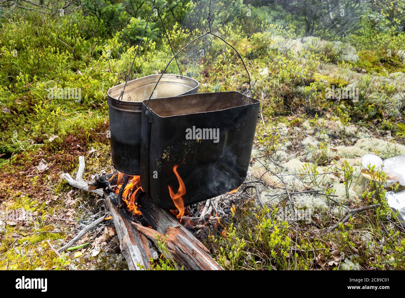 Cucinare cibo in condizioni di campo, in calderoni affumicati su un fuoco in una foresta in una radura. Il concetto di viaggio in famiglia e di svago all'aperto. Foto Stock