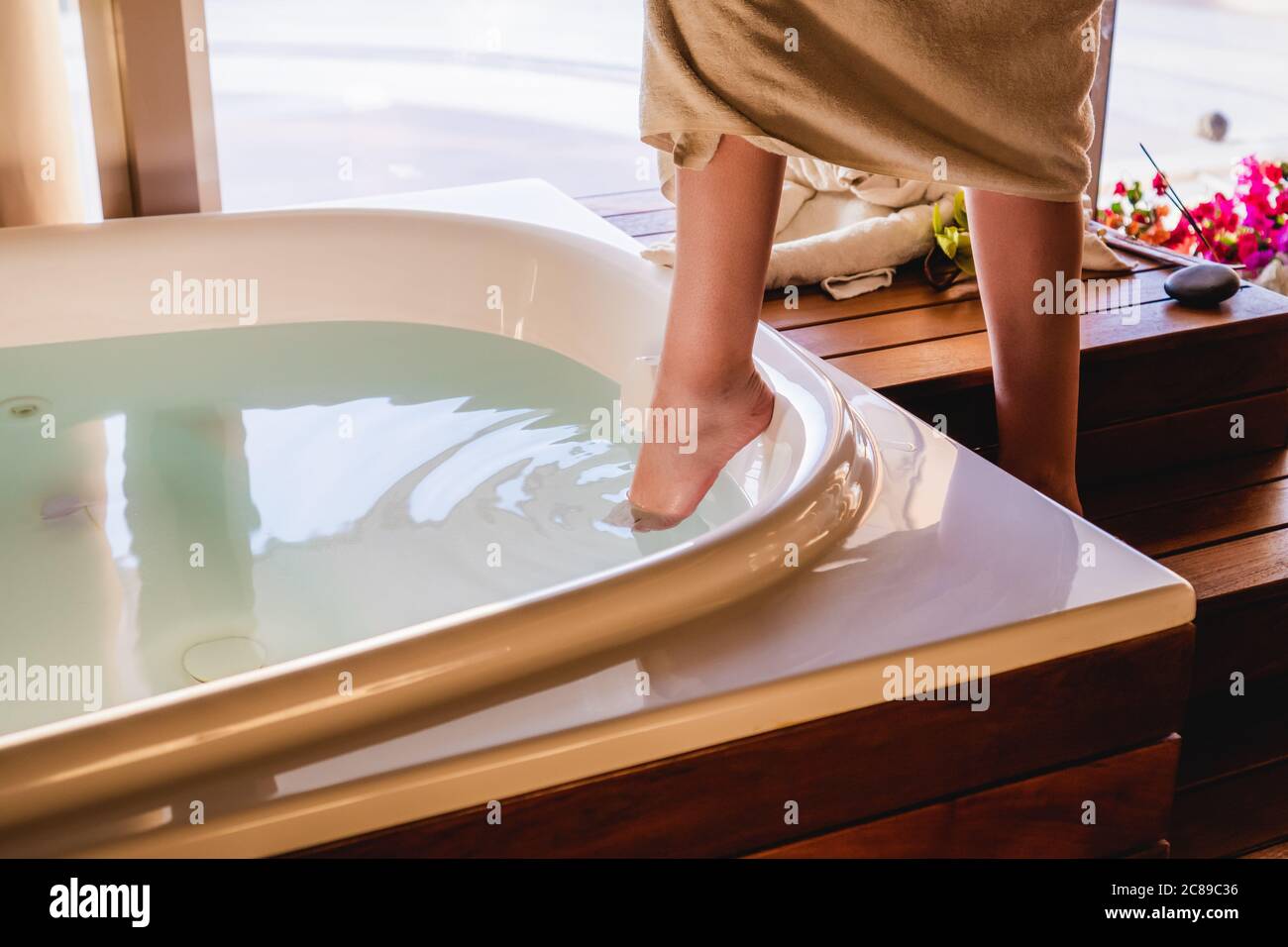 La donna tocca l'acqua con il piede per avere un bagno nella vasca da bagno. Foto Stock