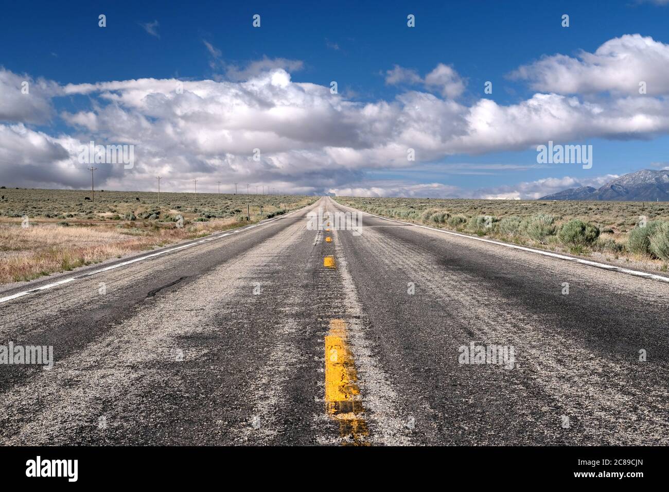 Vista bassa guardando giù una vecchia strada asfaltata battente che mostra la prospettiva drammatica all'orizzonte lungo la US 50 in Nevada Foto Stock