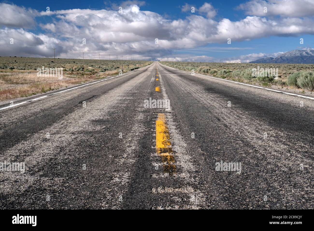 Vista bassa guardando giù una vecchia strada asfaltata battente che mostra la prospettiva drammatica all'orizzonte lungo la US 50 in Nevada Foto Stock