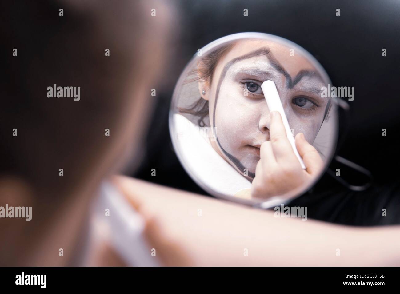 Ragazza giovane si trucco nella stanza di spogliatoio. Bambino di clown itinerante. Foto Stock