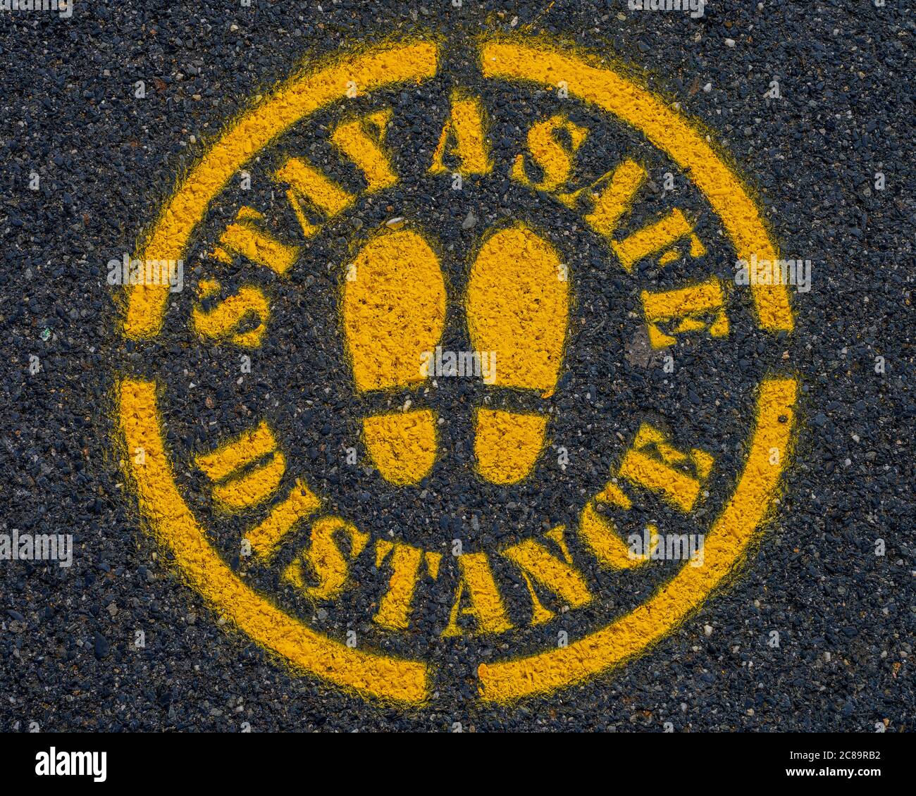 Covid-19 Stay a Safe Distance Sign sul marciapiede o strada. Foto Stock