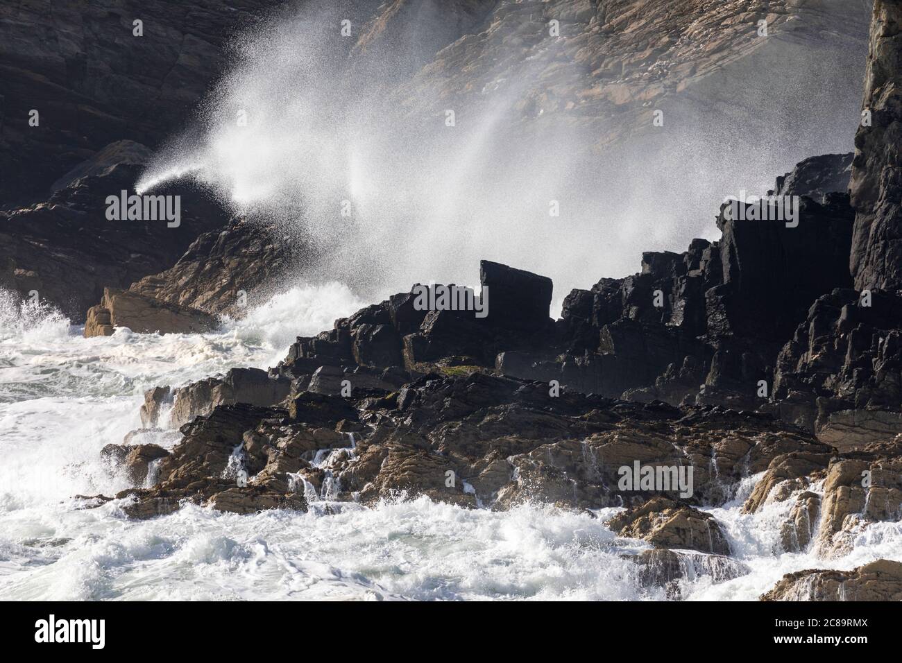 Le onde della tempesta si infrangono contro le coste rocciose di Anglesey, Galles del Nord Foto Stock