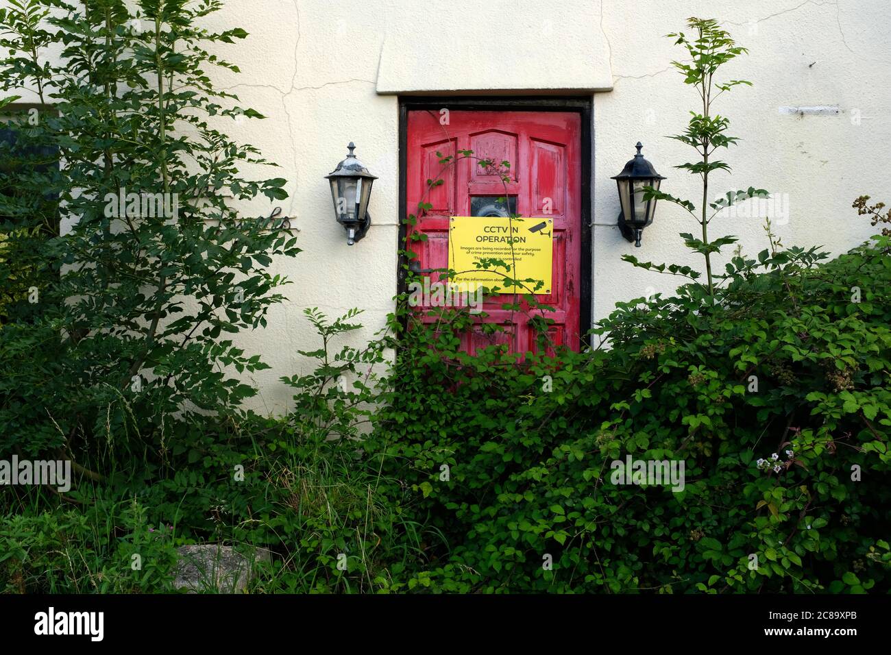 2020 luglio - porta rossa sopravfatta ad una casa deserta nel villaggio Somerset di Cheddar con cartello di sicurezza di avvertimento cctv Foto Stock