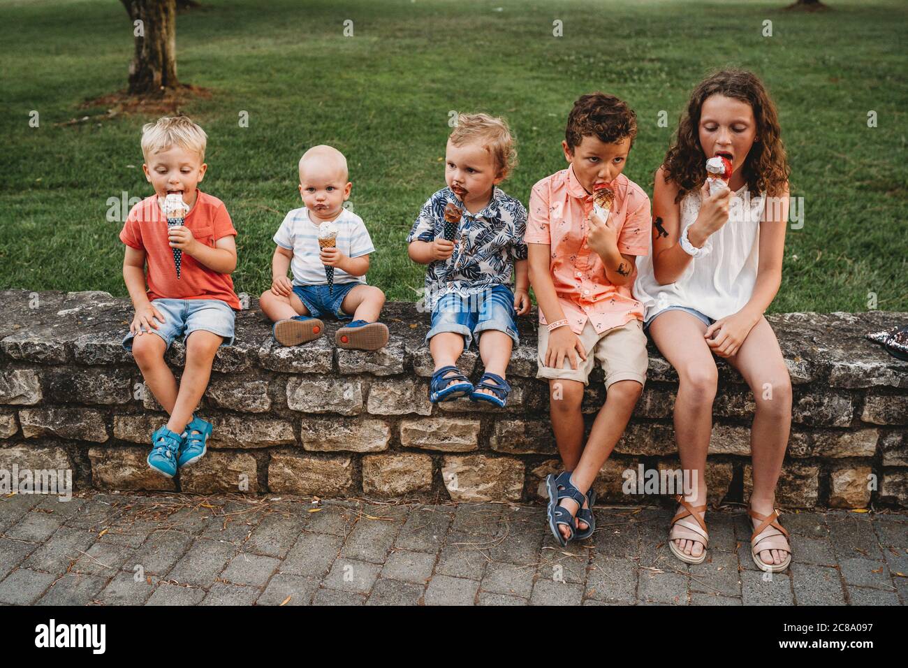 Famiglia bianca e bambini che mangiano insieme gelato durante le vacanze Foto Stock