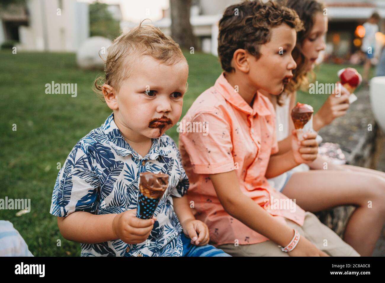 Fratelli con facce sporche mangiare gelato insieme durante la vacanza Foto Stock