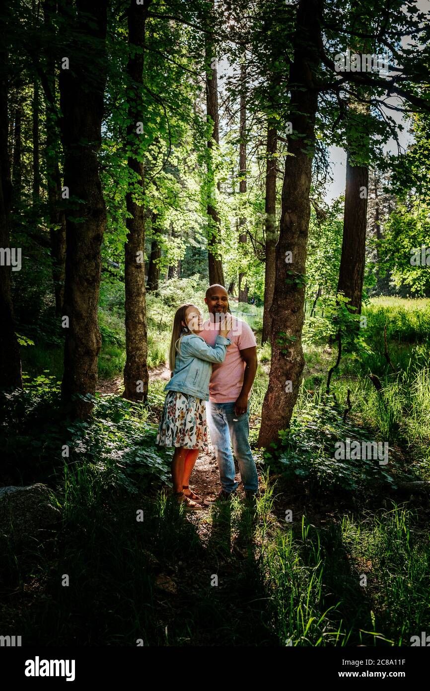 Coppia biraciale in piedi e ridendo nella foresta Foto Stock