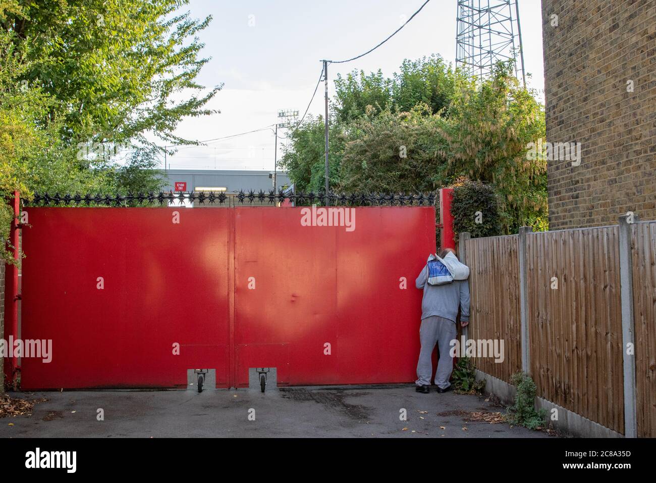 Londra, Regno Unito. 22 luglio 2020. Un fan cerca di dare un'occhiata attraverso le porte di Griffin Park. Il Brentford FC affronta quella che potrebbe essere la loro ultima partita a Griffin Park, Barnsley essendo l’avversario di questa sera. Brentford richiede solo un punto in più rispetto a West Brom per garantire la promozione automatica nella Premier League. Credit: Liam Asman/Alamy Live News Foto Stock