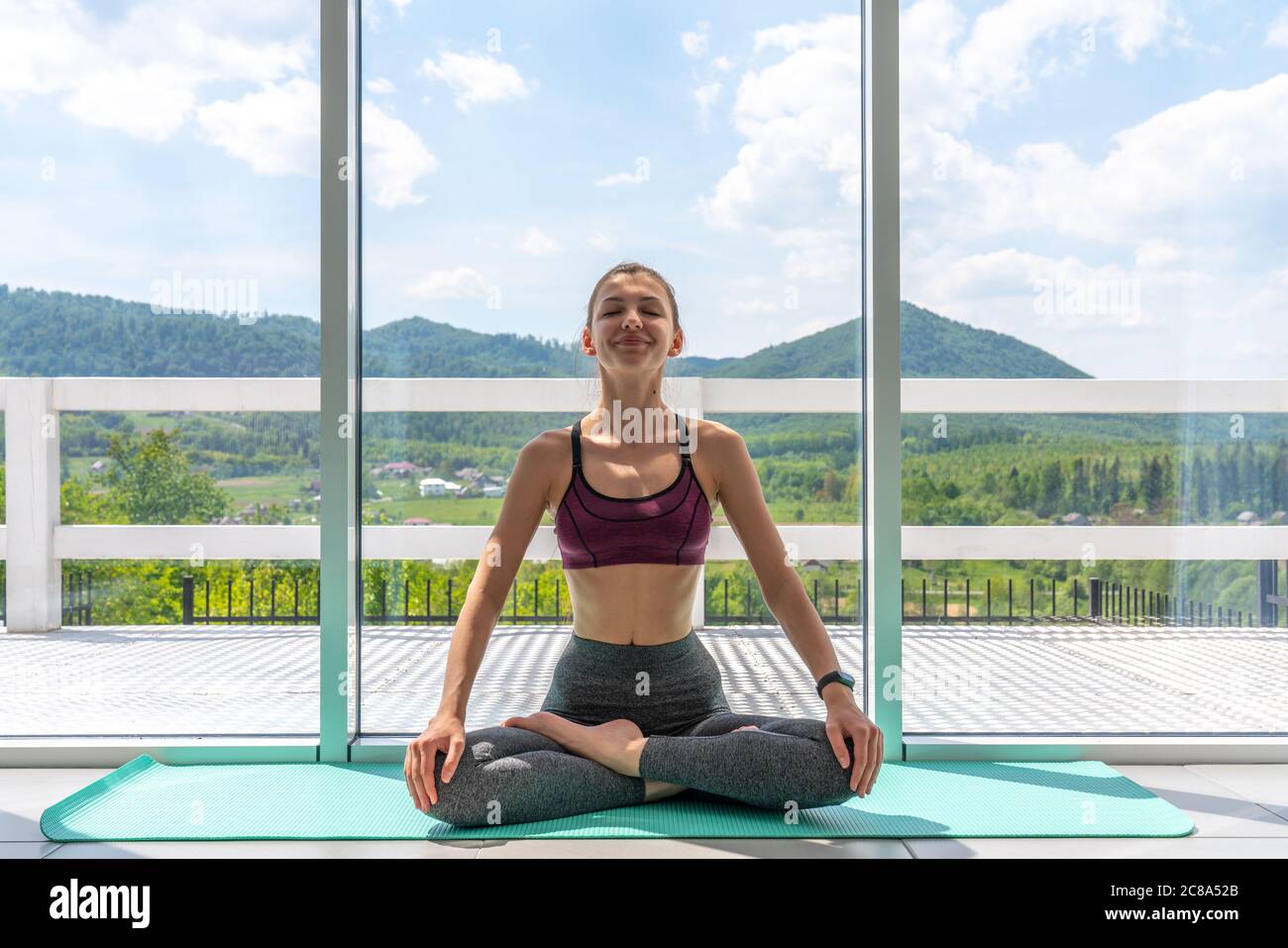 Giovane bella donna che pratica yoga con vista sulle montagne sullo sfondo. Concetto di benessere Foto Stock