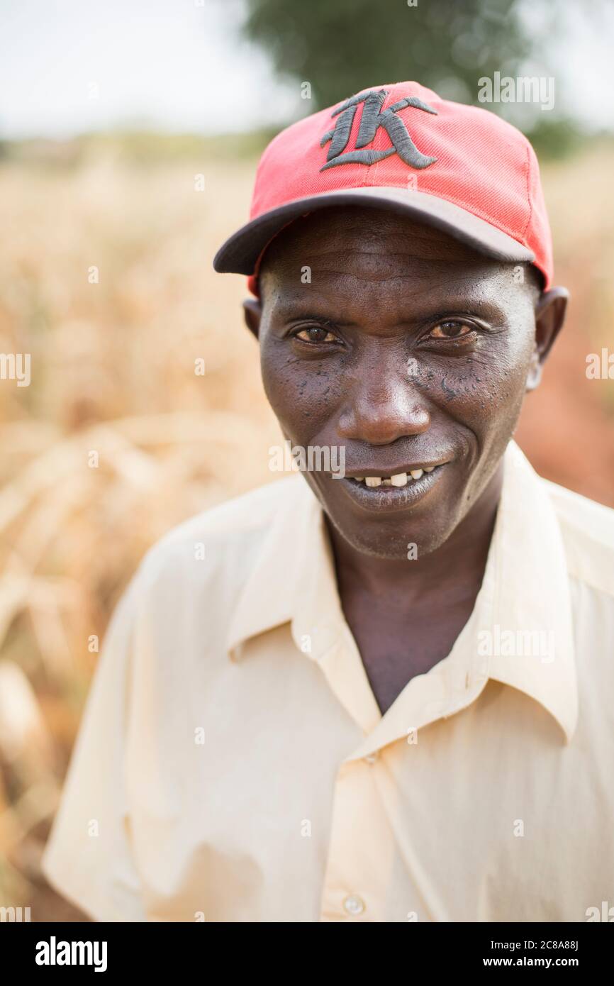 Ritratto di un uomo in un cappello rosso con un sorriso sly - Makueni County, Kenya, Africa orientale. Foto Stock