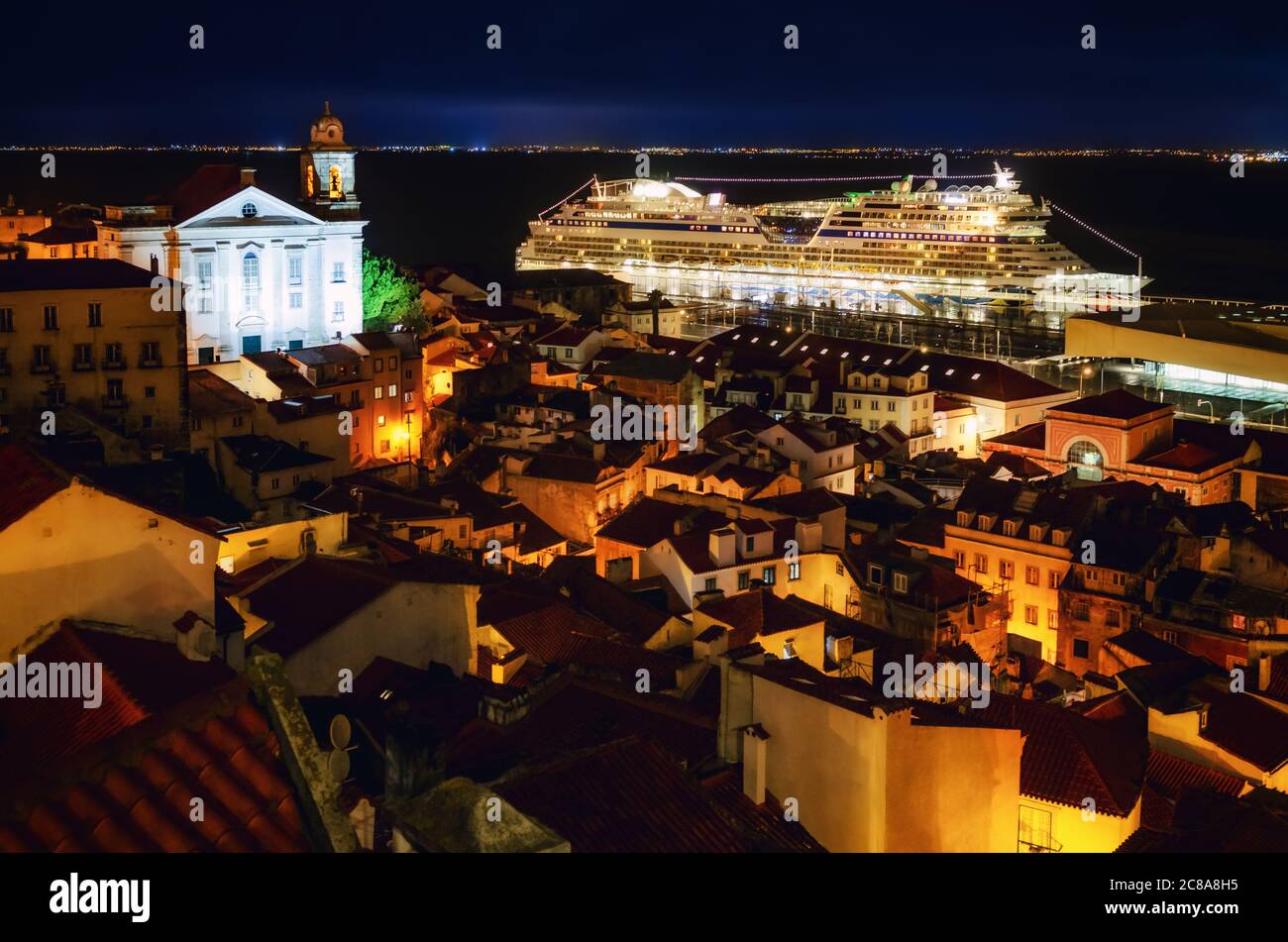 Vista notturna di Lisbona (Portogallo) navi da crociera porto dal miraduro di Santa Luzia, terrazza belvedere sulle strade del quartiere di Alfama, con il ch Foto Stock