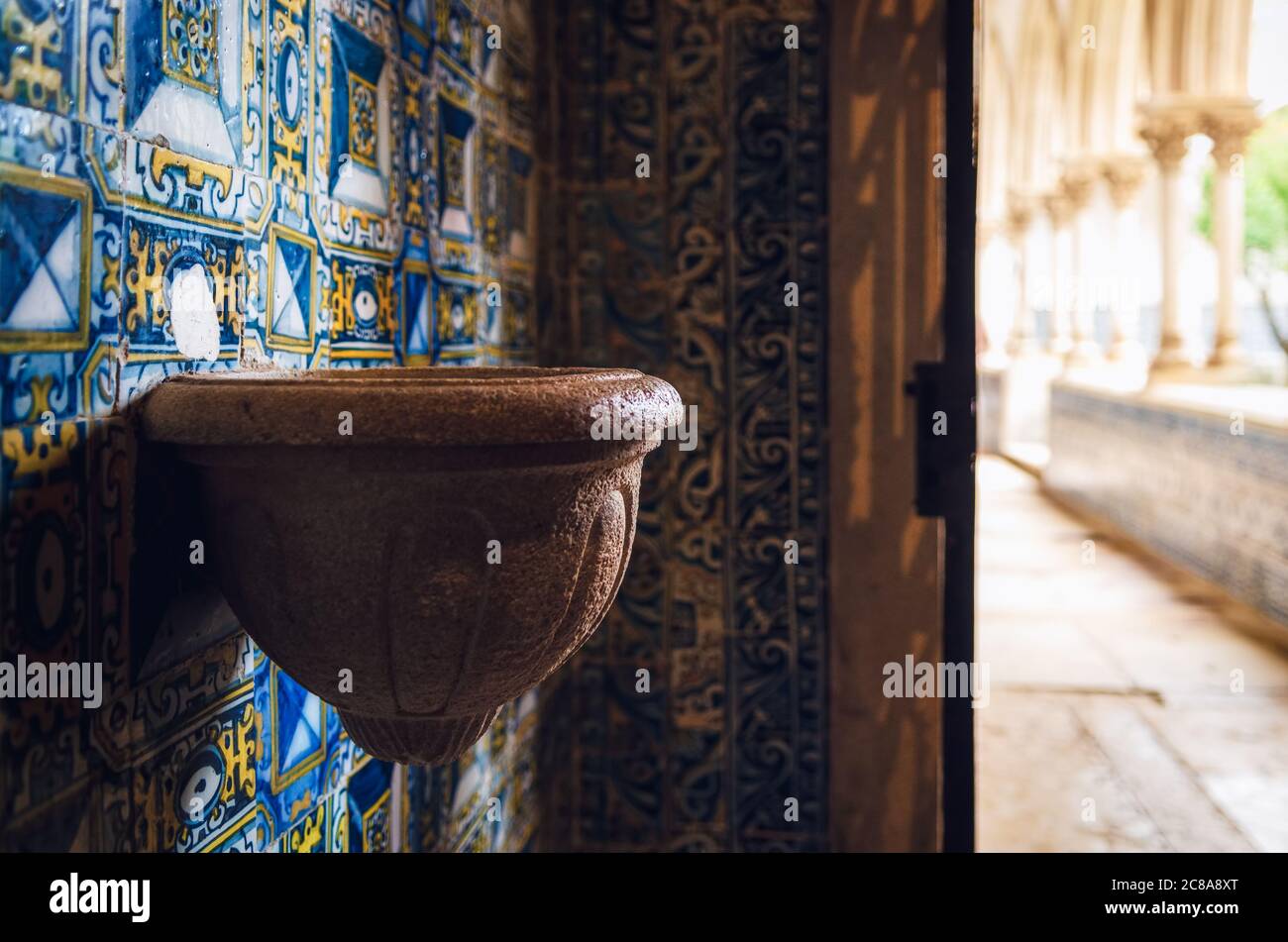 antica pietra fonte d'acqua santa in una cappella di un monastero portoghese medievale, decorata con tradizionali piastrelle dipinte blu Foto Stock