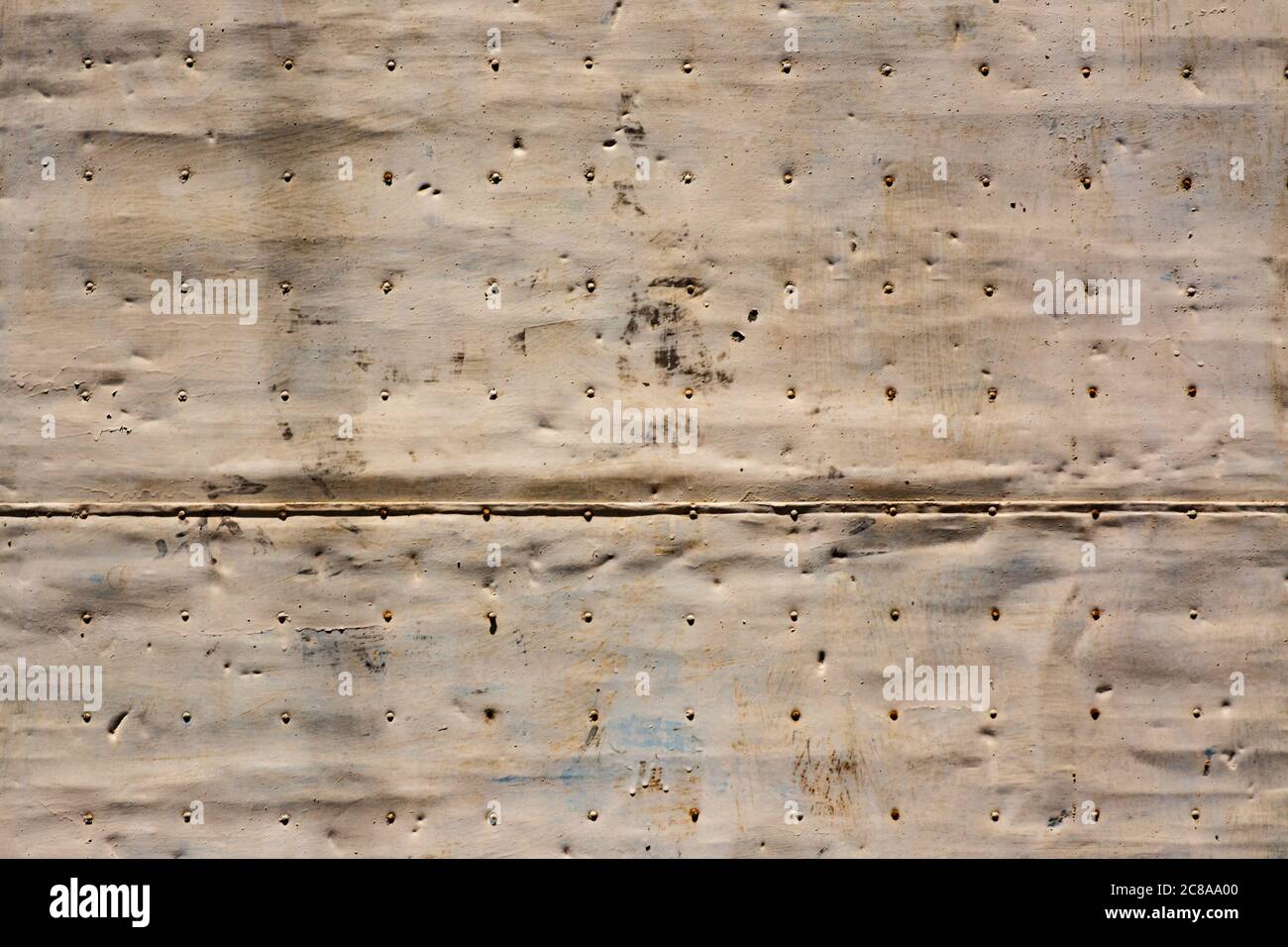 Vecchio pannello in metallo macchiato, battuto e arrugginito in una porta con chiodi in file. Immagine per sfondi o disegni Foto Stock