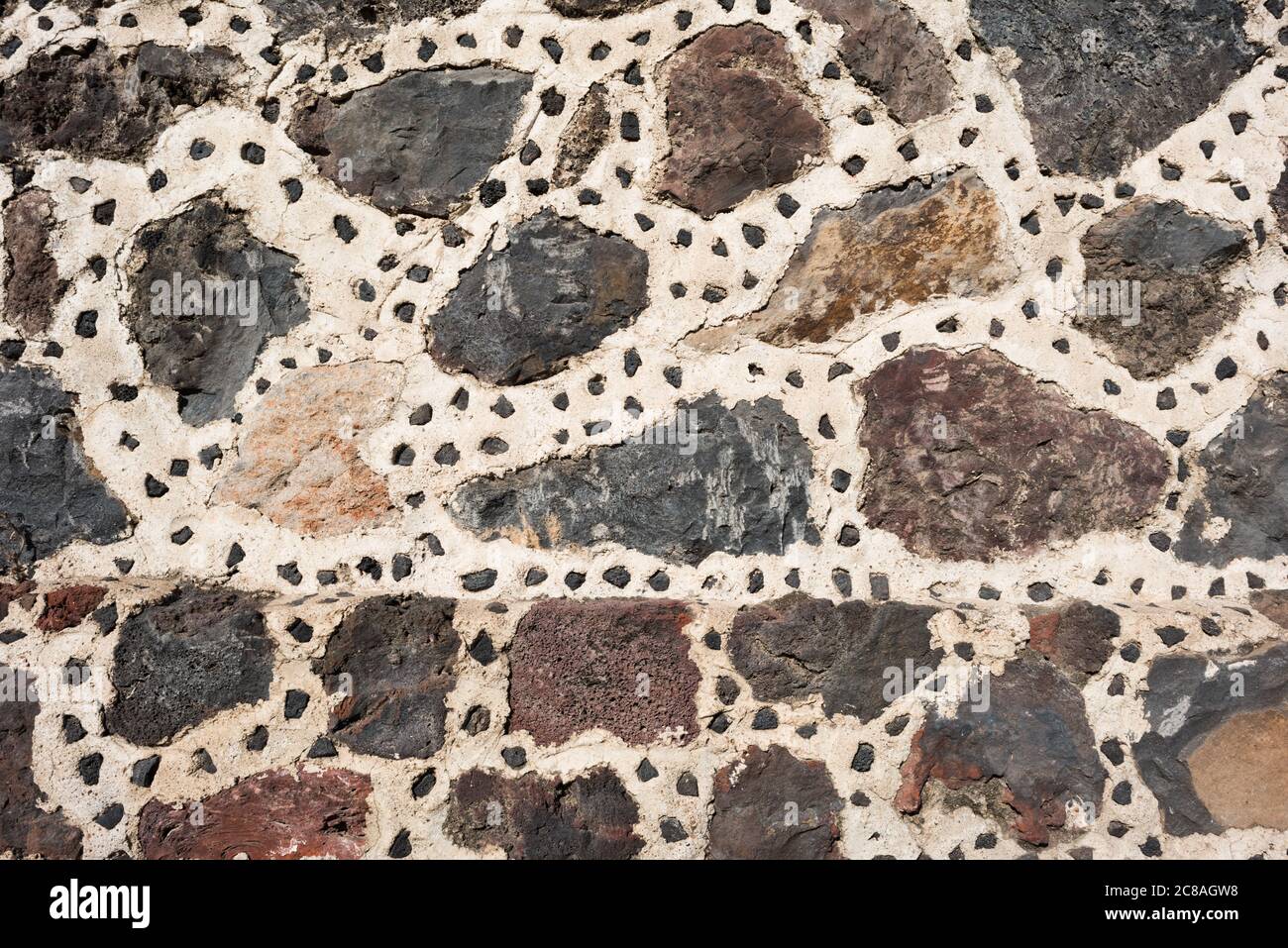 Sito archeologico di Teotihuacan muro di pietra Messico // TEOTIHUACAN, Messico - strutture in pietra e Malta ricostruite presso il sito archeologico di Teotihuacan mostrano sforzi di restauro in questa antica città mesoamericana. Gli elementi ricostruiti forniscono un'idea dell'architettura originale di questa metropoli precolombiana, fiorita tra il 100 e il 650 d.C. circa. Teotihuacan era uno dei più grandi centri urbani del mondo antico, con una popolazione che potrebbe aver raggiunto i 100.000 - 200.000 abitanti al suo apice. Il sito archeologico, situato a circa 25 miglia (40 chilometri) a nord Foto Stock