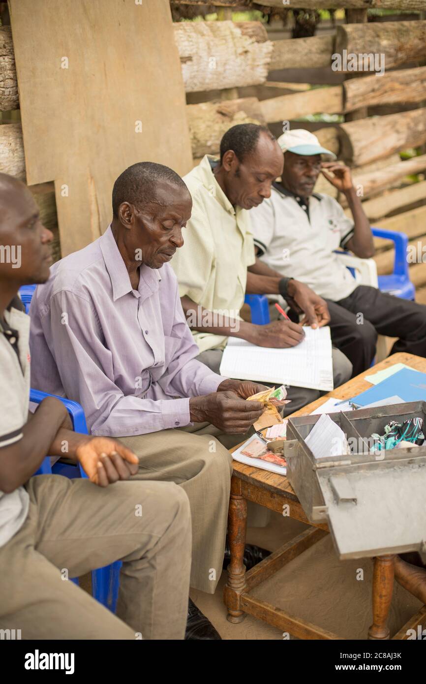 Gli abitanti di un gruppo bancario della comunità della microfinanza si riuniscono per salvare e prestare tra loro nel distretto di Masaka, Uganda, Africa orientale. Foto Stock