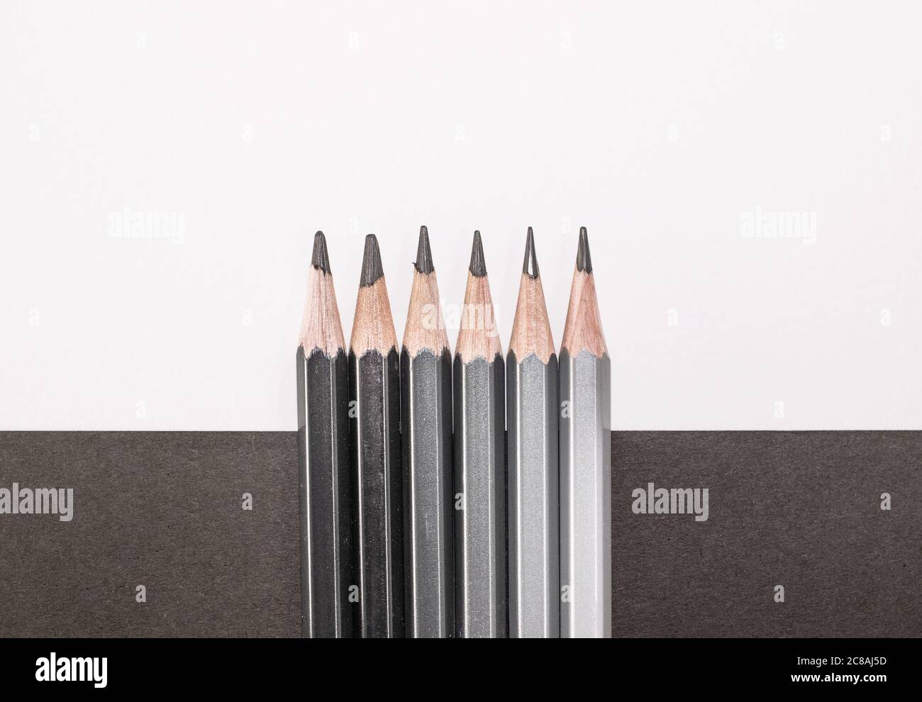 Fila di matite scure su sfondo bianco e nero, con spazio per la copia Foto Stock