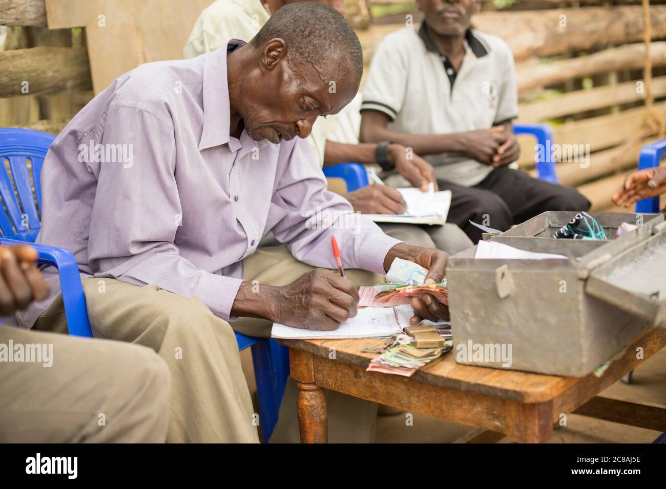 Gli abitanti di un gruppo bancario della comunità della microfinanza si riuniscono per salvare e prestare tra loro nel distretto di Masaka, Uganda, Africa orientale. Foto Stock