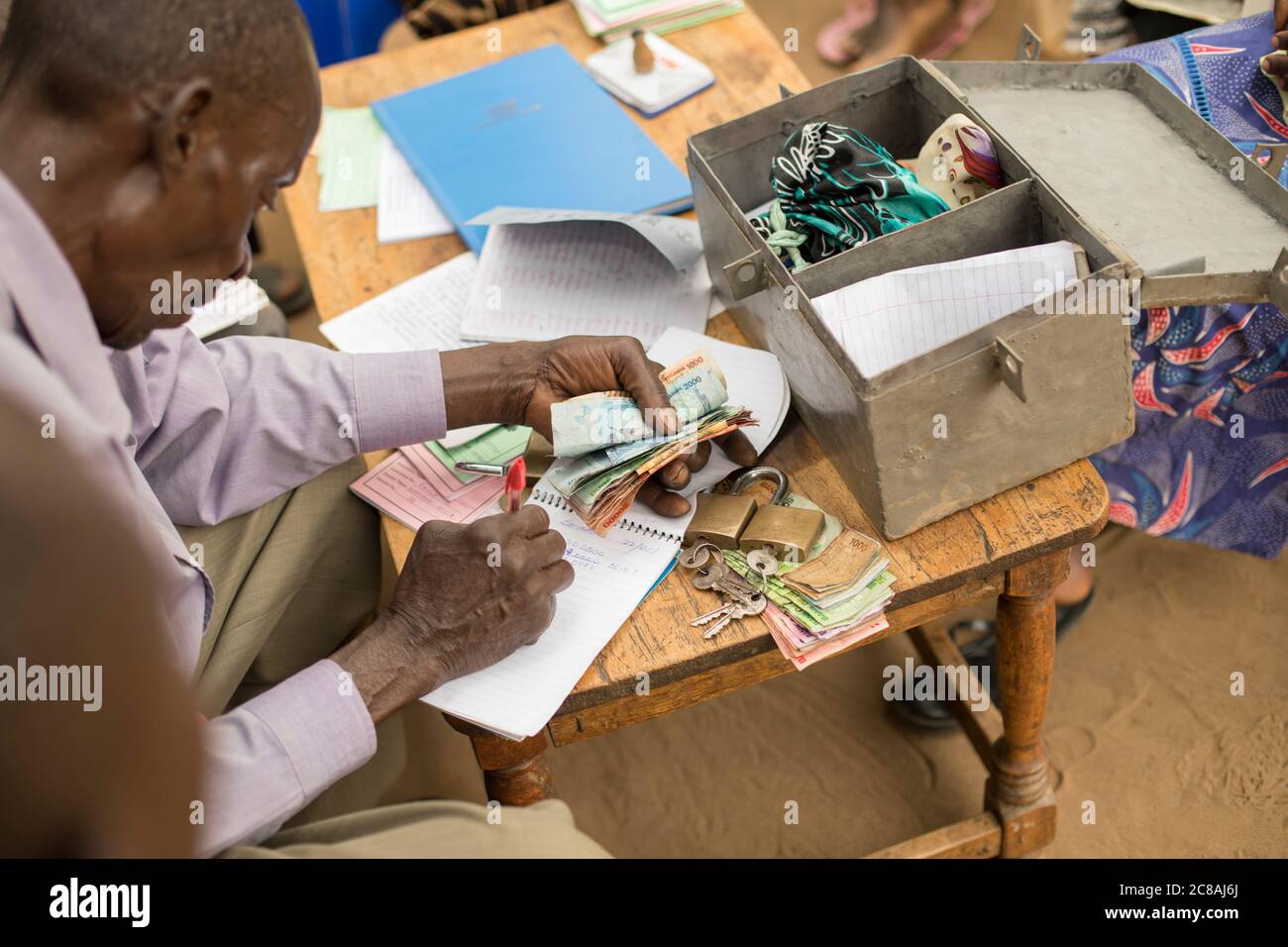 Gli abitanti di un gruppo bancario della comunità della microfinanza si riuniscono per salvare e prestare tra loro nel distretto di Masaka, Uganda, Africa orientale. Foto Stock