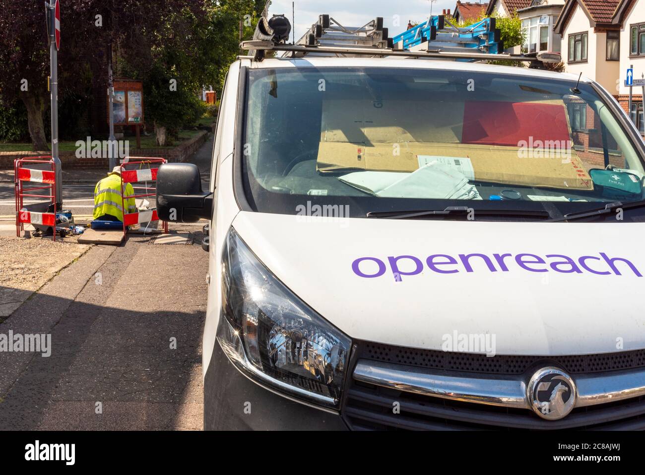 Operaio Openreach con furgone. Telecomunicazioni in corso con lavori maschili in un pannello di accesso pavimentato. Progettazione di barriere di sicurezza Foto Stock