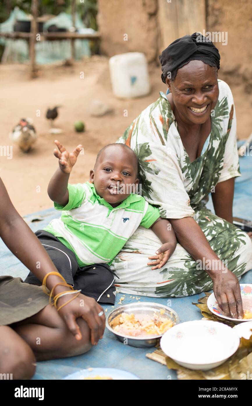 Una famiglia è seduta fuori casa per condividere un pasto insieme nel distretto di Kyotera, Uganda, Africa orientale. Foto Stock