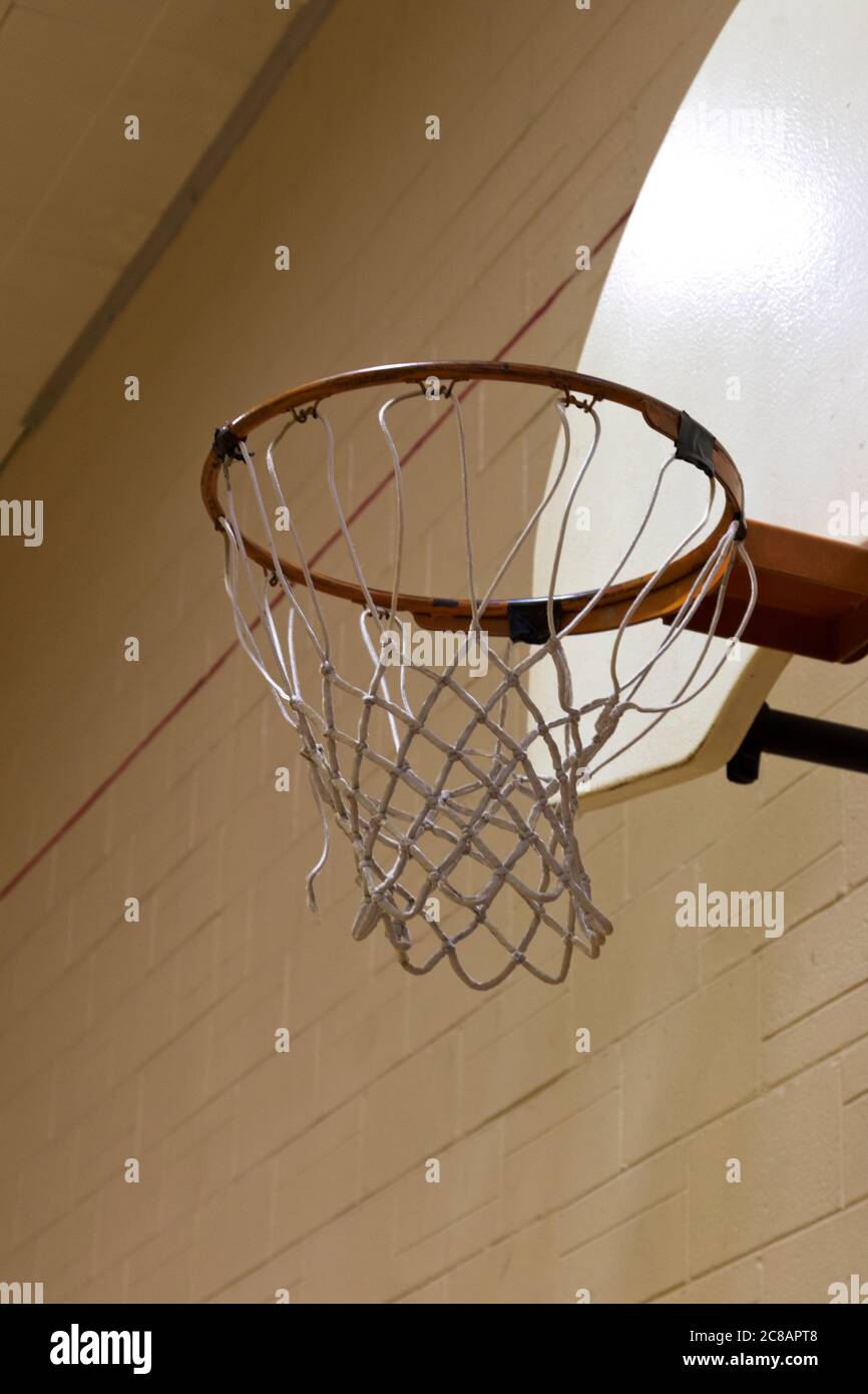 La rete di basket con backboard è ancora in palestra scuola silenziosa come simbolo di chiusura o di annullamento di scuola, giochi, educazione fisica, sport di squadra Foto Stock
