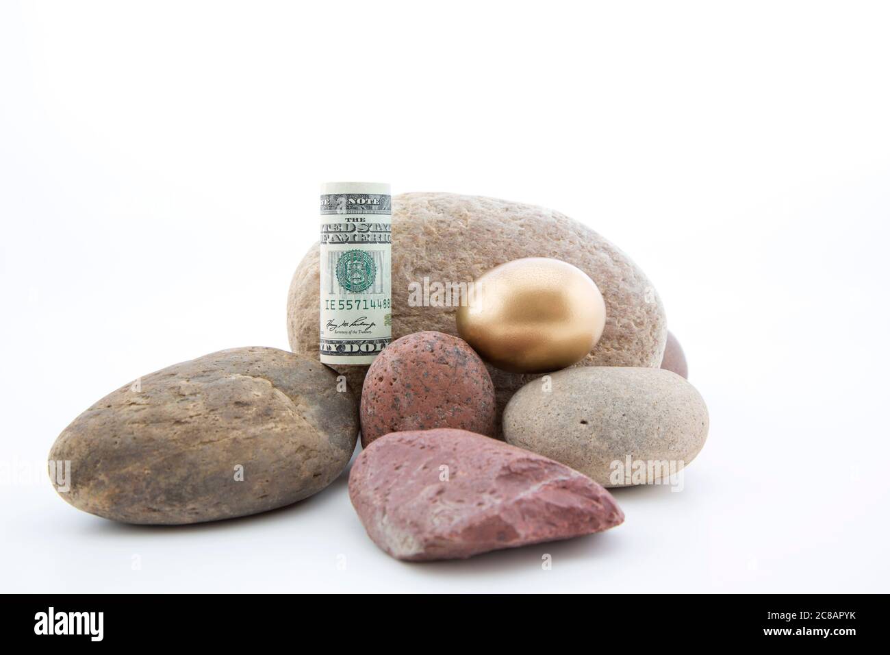 A rischio i concetti di successo economico e finanziario visti in simbolico oro uovo e valuta messo sulle rocce Foto Stock
