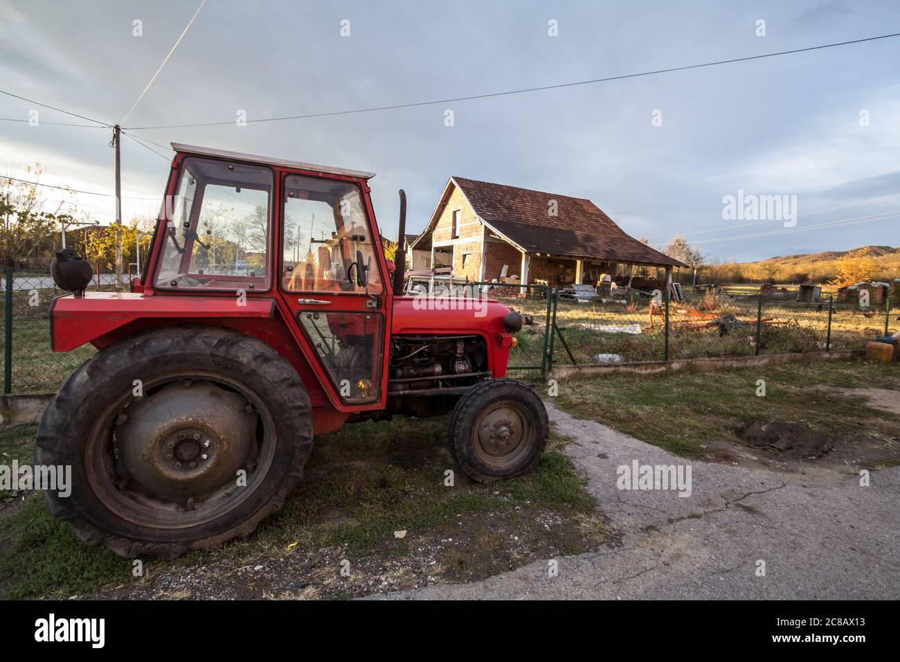 KRALJEVO, SERBIA - 10 NOVEMBRE 2019: Trattore di fronte ad una fattoria nella campagna della Serbia, in un tipico terreno agricolo rurale della regione di S. Foto Stock