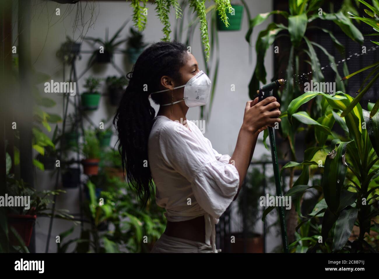 Giovane donna che fa giardinaggio in maschera facciale Foto Stock