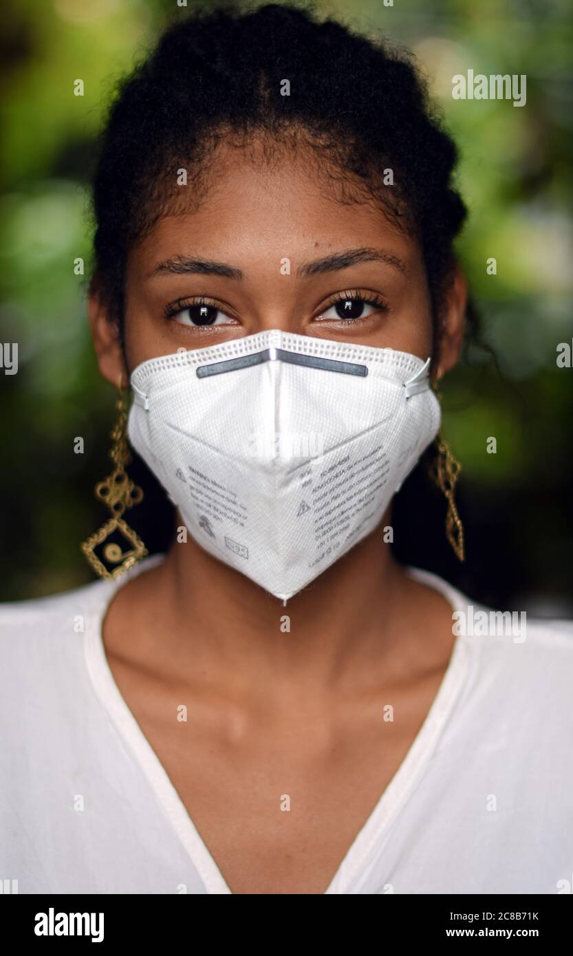 Giovane donna nera con una maschera facciale che guarda la fotocamera Foto Stock