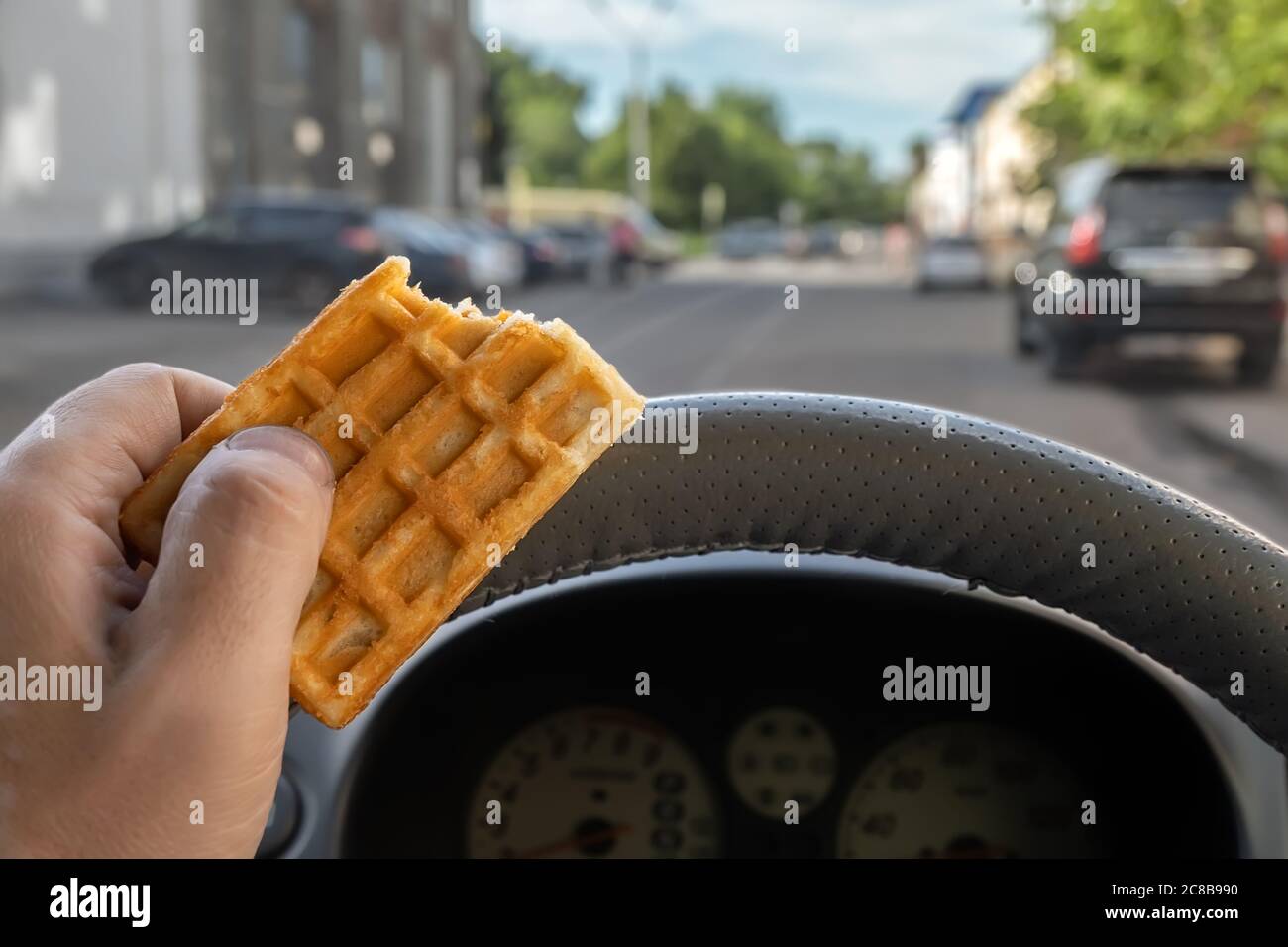 cibo, biscotti in mano a un autista mentre si guida in città Foto Stock